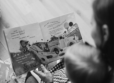 Parent reading to a toddler in her lap