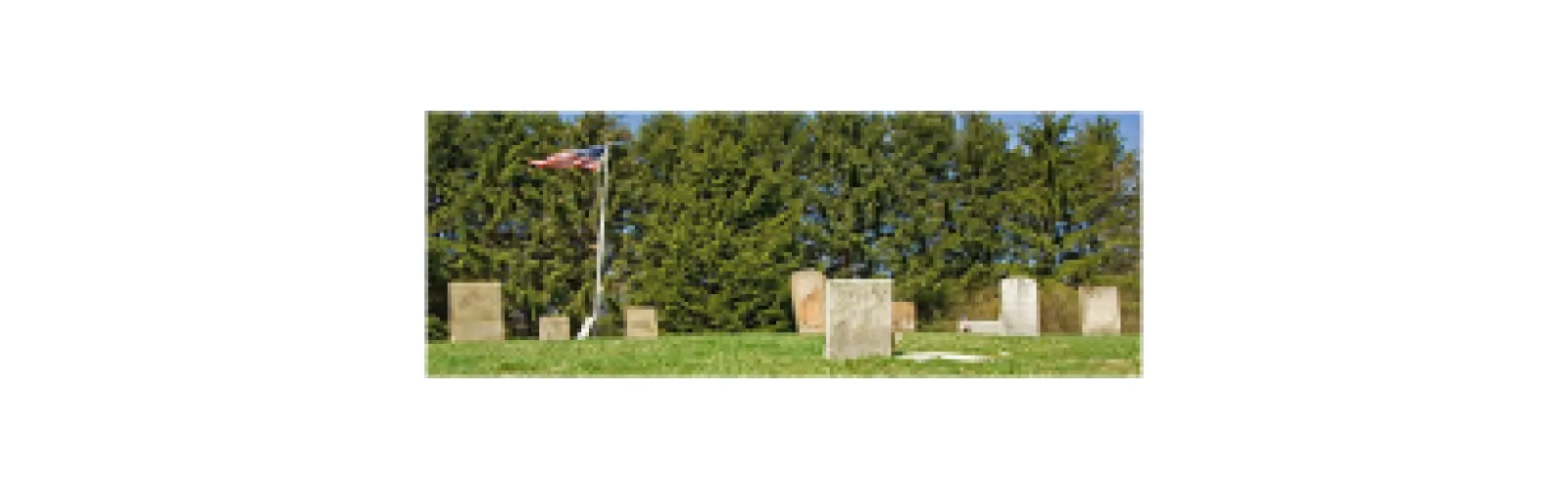 A cemetary with old headstones and an American flag.